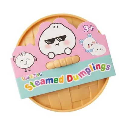 A toy set of squeezable steamed dumplings shaped like a bamboo steamer basket, with a colorful retail card showing cartoon dumpling illustrations and the text 'SQUEEZING Steamed Dumplings' and '3+'.